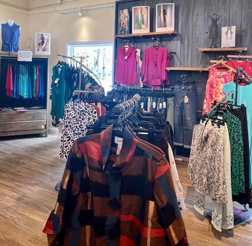 Clothing store interior with racks of women's apparel in various colors.
