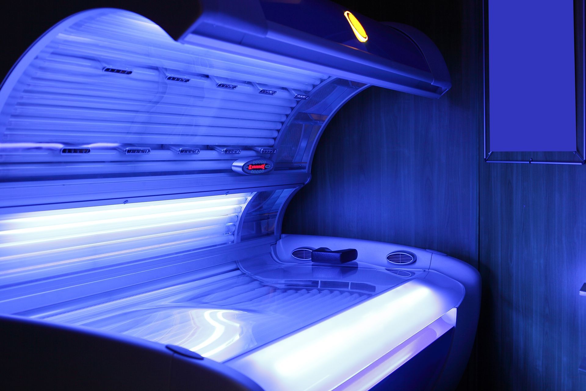 A tanning bed with blue lights on it in a dark room.
