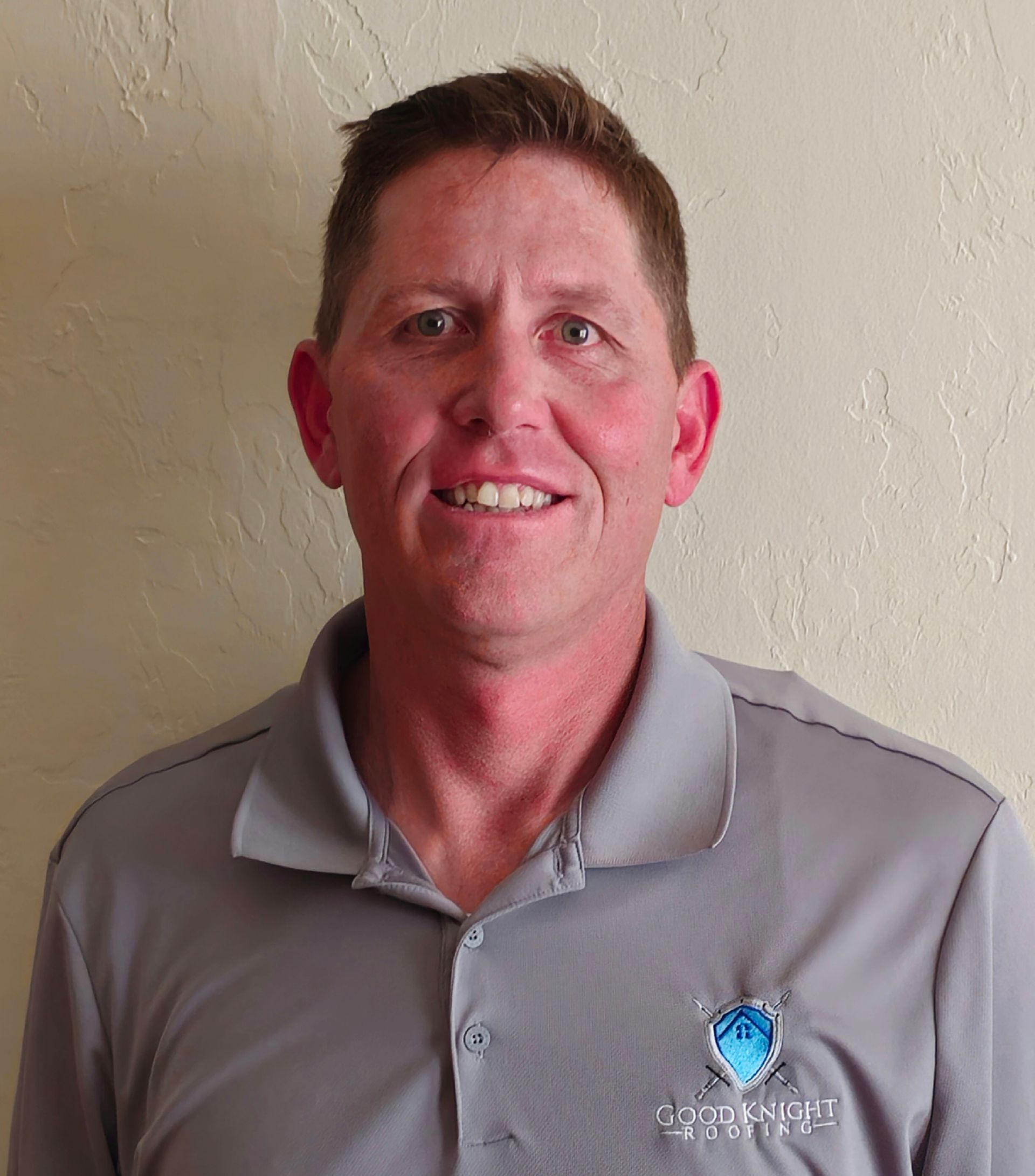 A man wearing a grey shirt with a logo on it