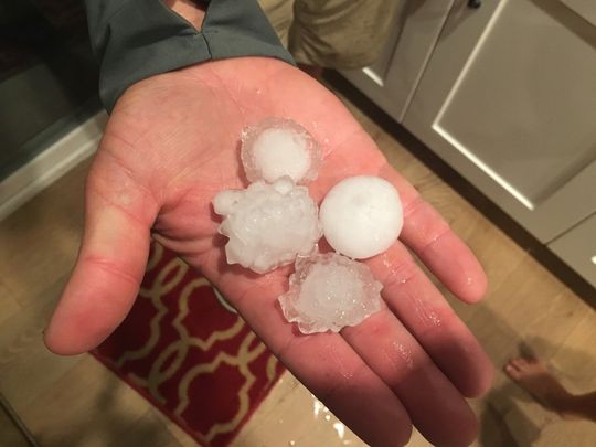 A person is holding a handful of hail in their hand