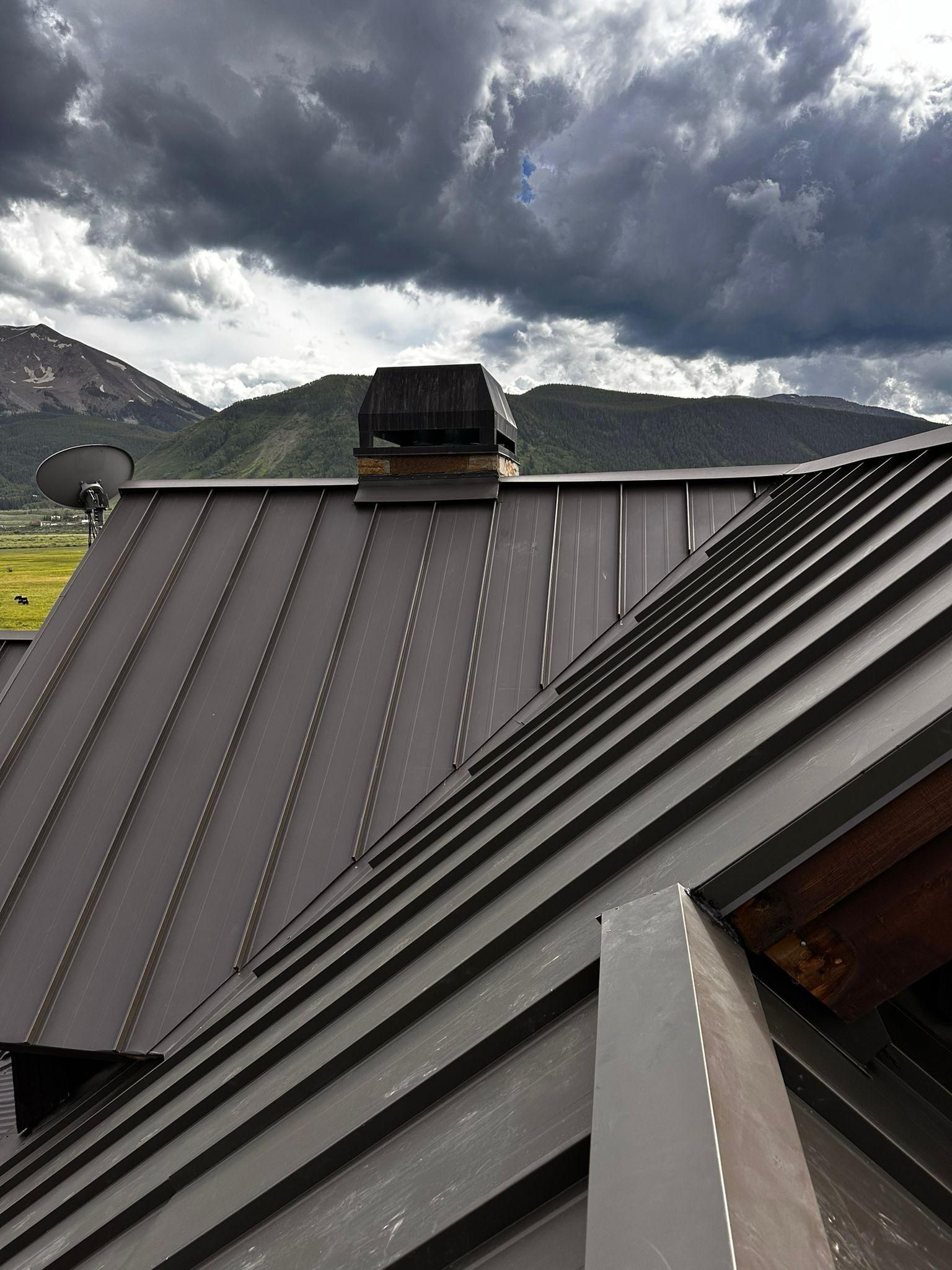 A roof with a chimney on top of it and mountains in the background