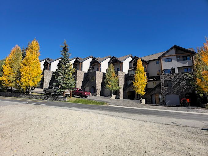 A red truck is parked in front of a large apartment building