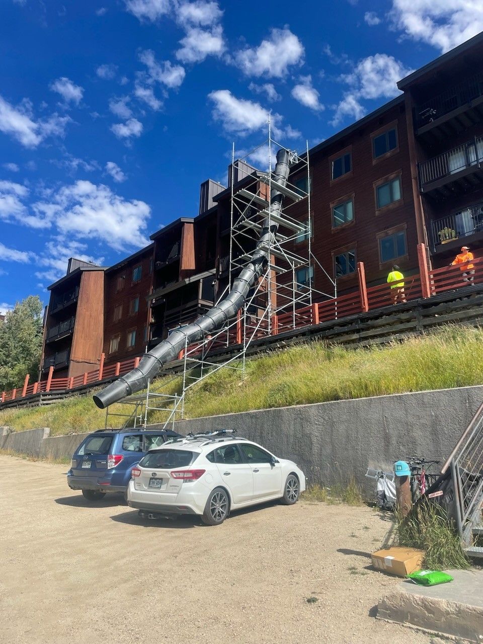 A white car is parked in front of a large building