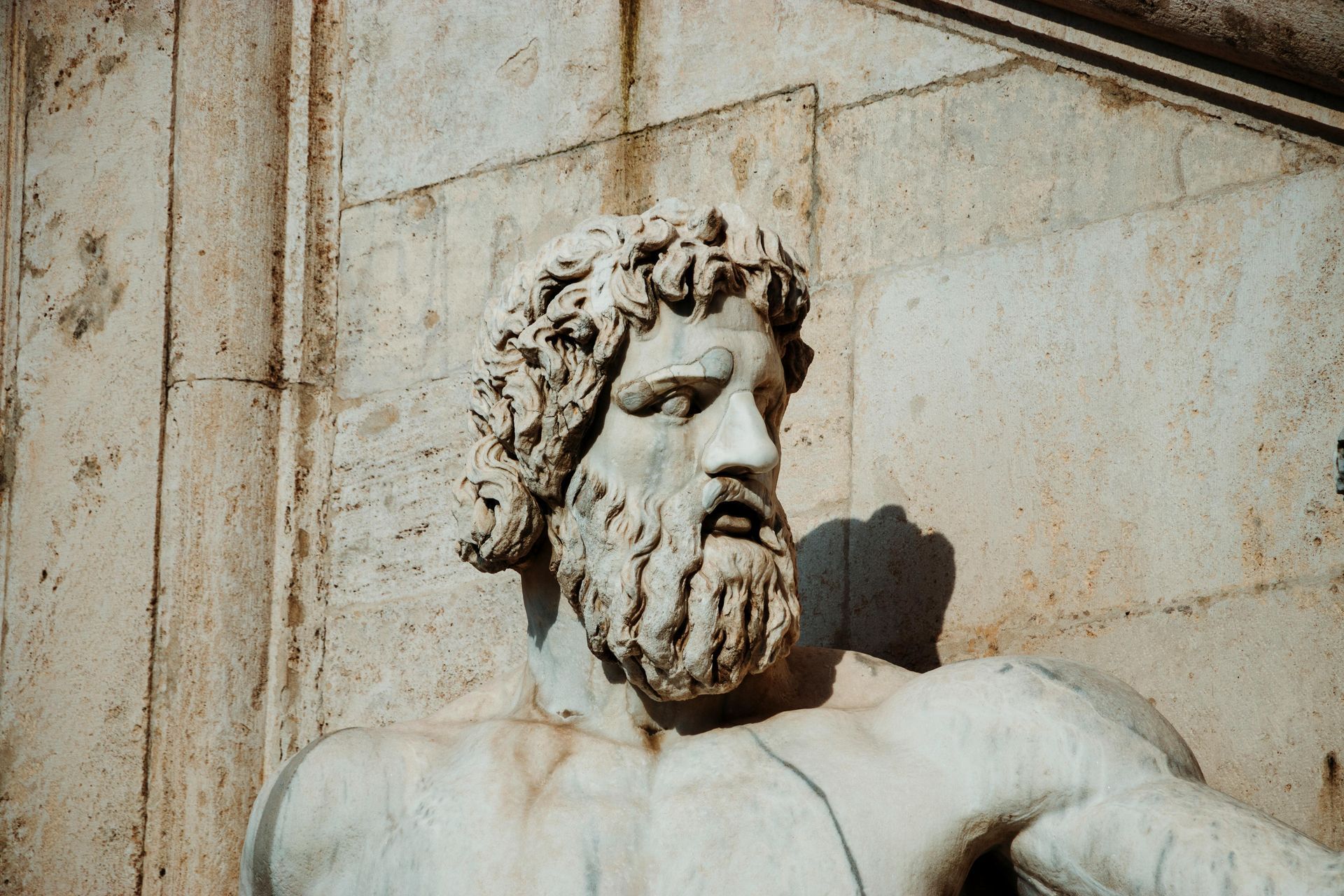 A statue of a man with a beard is against a brick wall