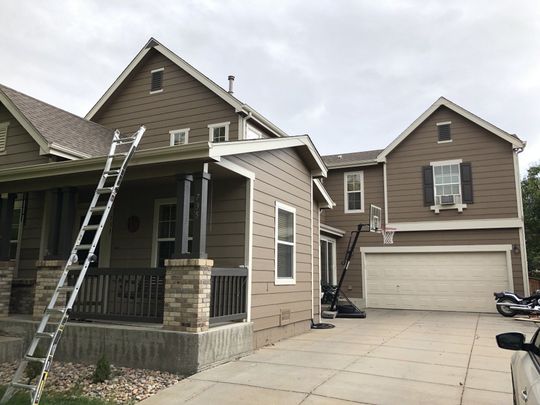 A house with a ladder in front of it and a truck parked in front of it.