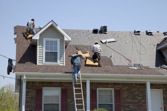 Two men are working on the roof of a house