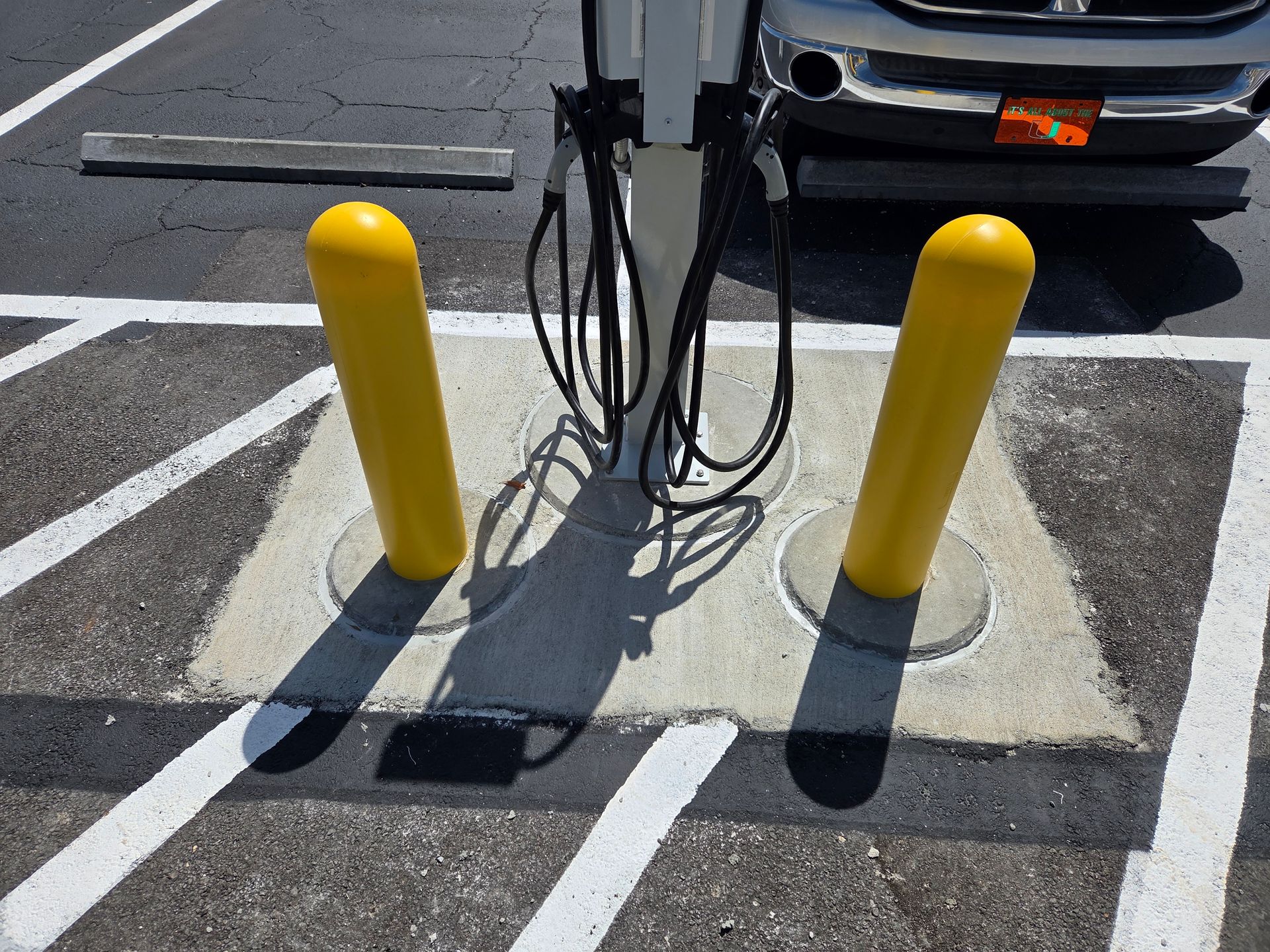 Yellow bollards protecting EV charging station cables.