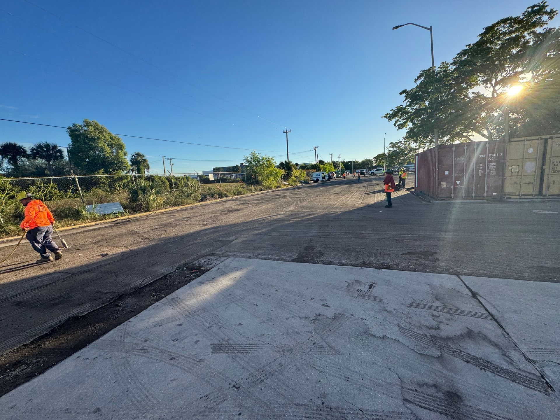 Workers paving a road under a sunny sky.