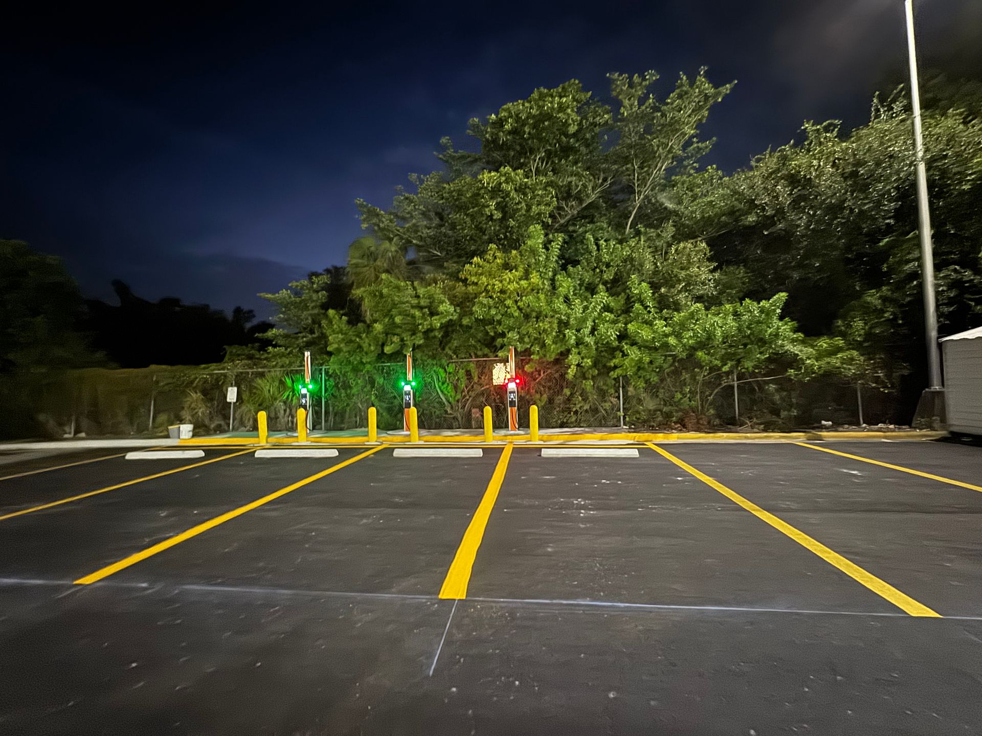 Parking lot with illuminated parking space indicators: green and red lights. Dark night sky.