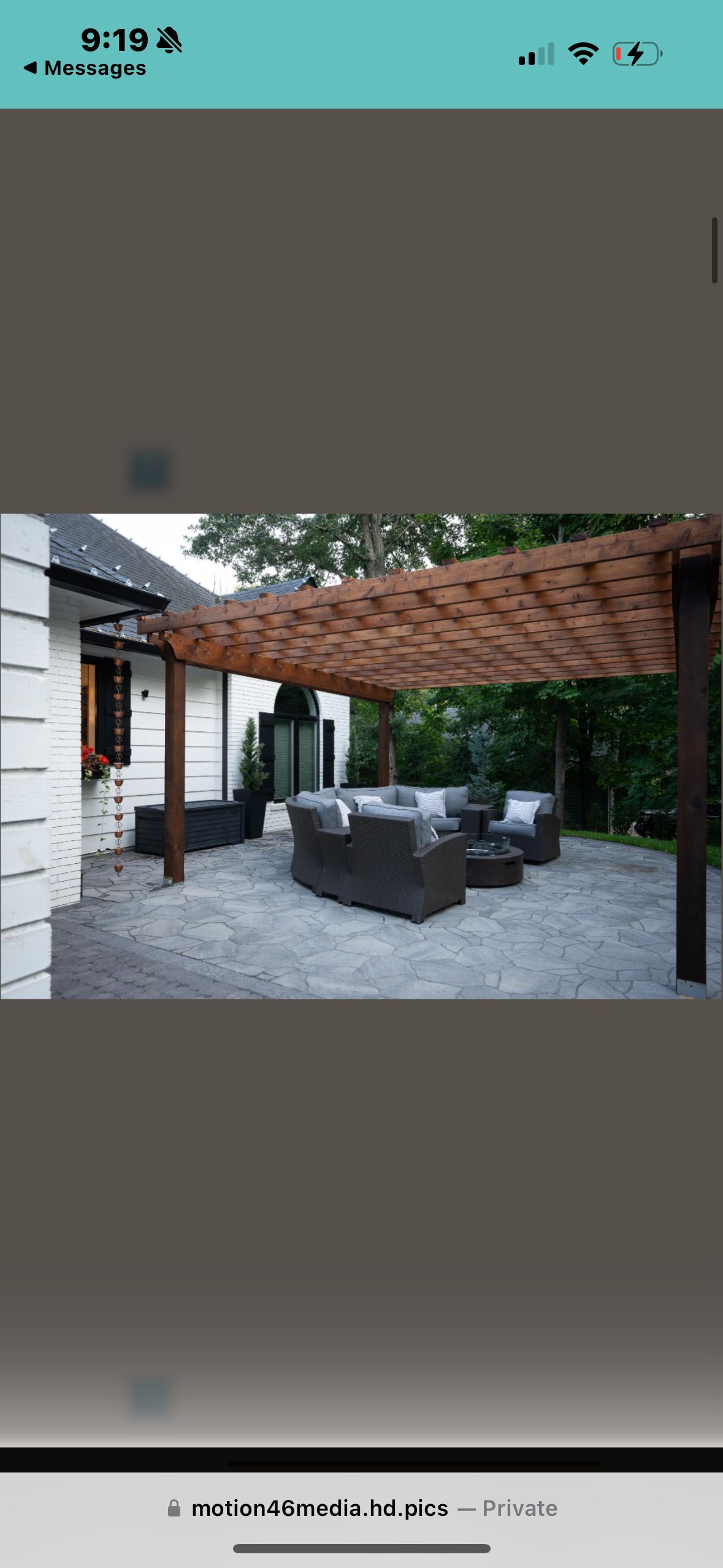 Outdoor seating area with a pergola, gravel ground, and house in the background.