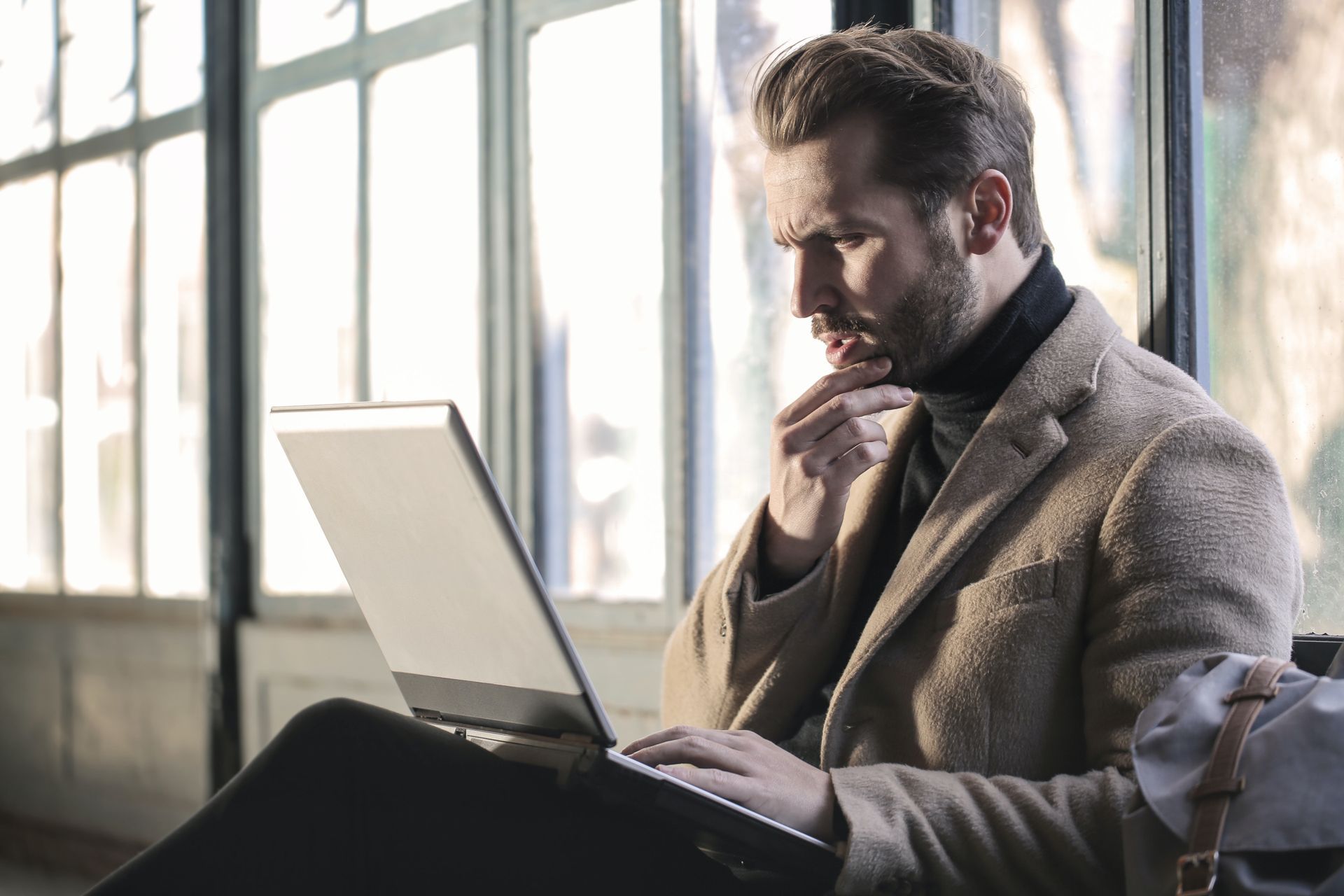 Man with a laptop in his lap looking inquisitive