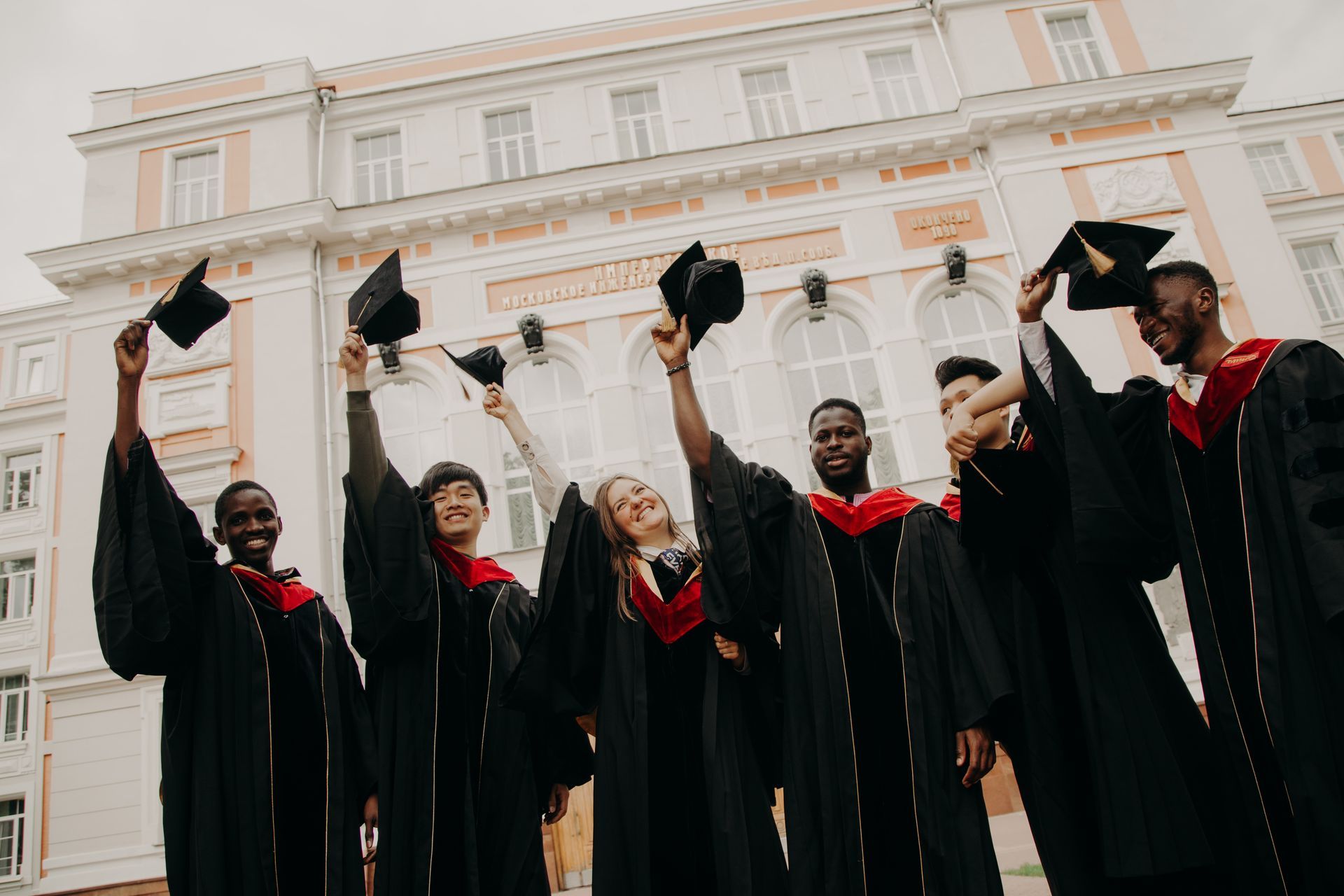 Group of graduates smiling and holding their hats and tassels in the air