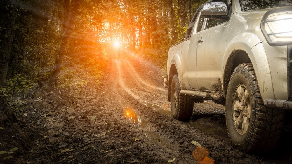 A Truck Is Driving Down A Muddy Road In The Woods — Maitland 4WD Centre In Cessnock, NSW