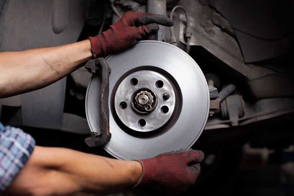 A Man Is Fixing A Brake Disc On A Car — Maitland 4WD Centre In Maitland, NSW