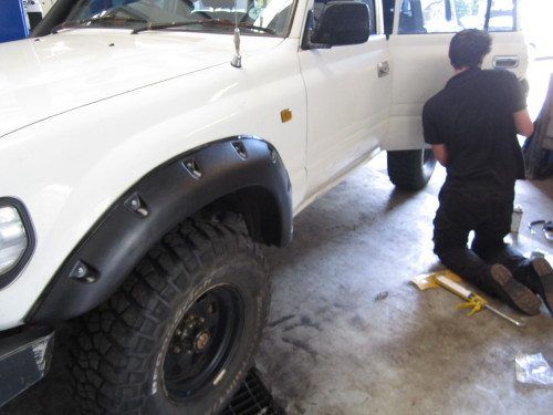 A Man Is Working Next To A White Truck In A Garage — Maitland 4WD Centre In Maitland, NSW