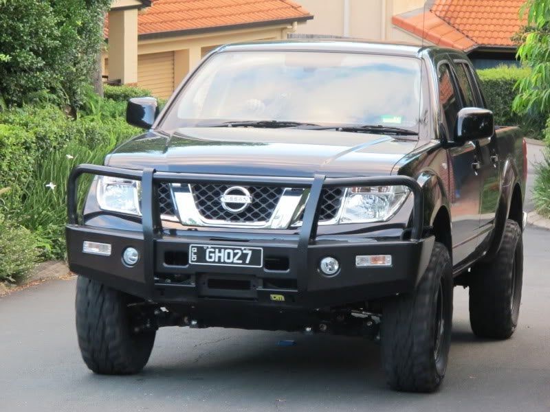 A Black Truck With A License Plate Is Driving Down A Street — Maitland 4WD Centre In Maitland, NSW