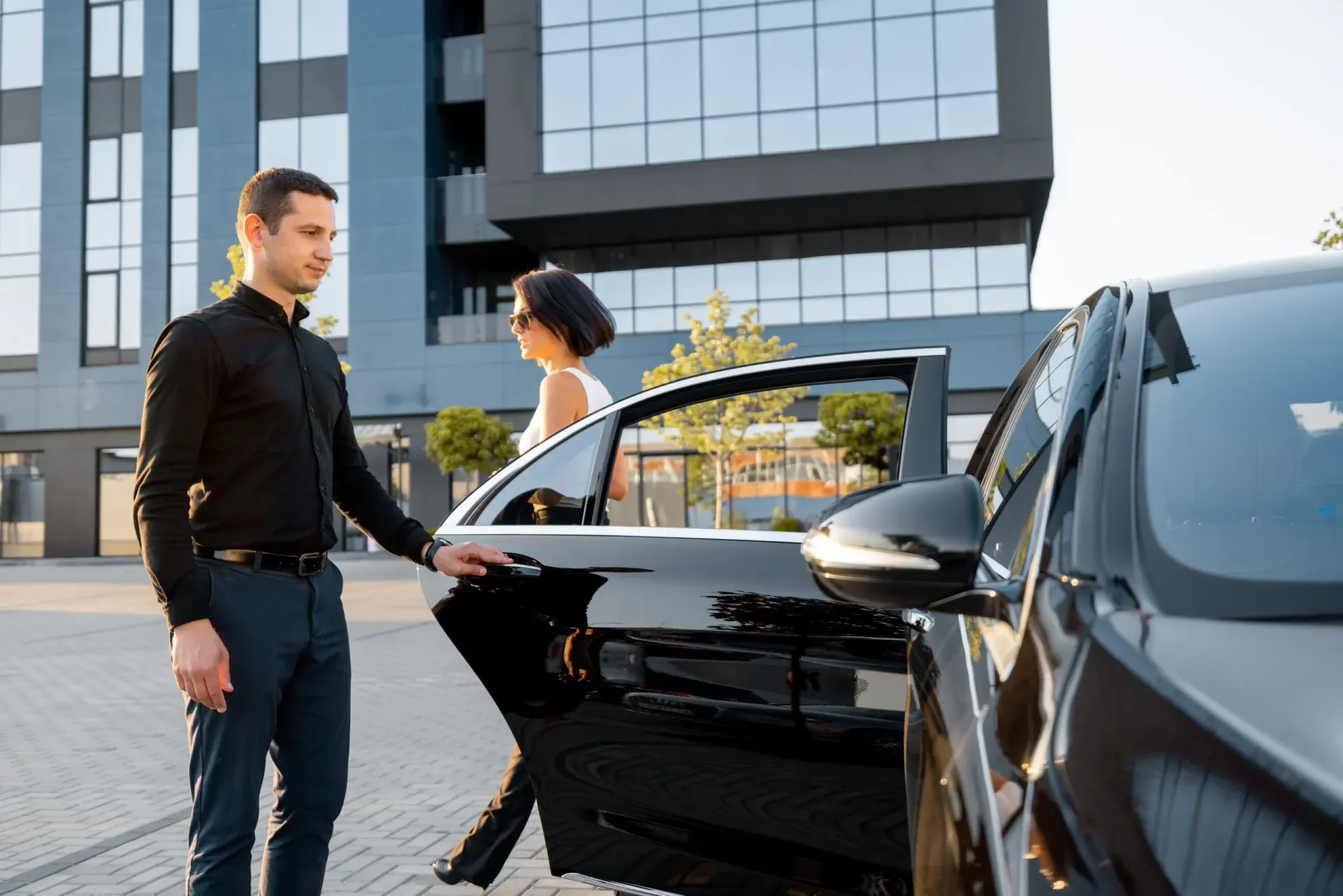 A man is helping a woman get out of a car.