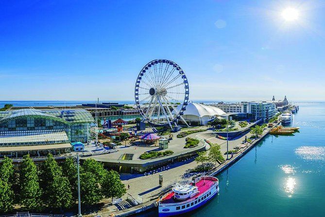 An aerial view of a ferris wheel and a boat in a harbor.