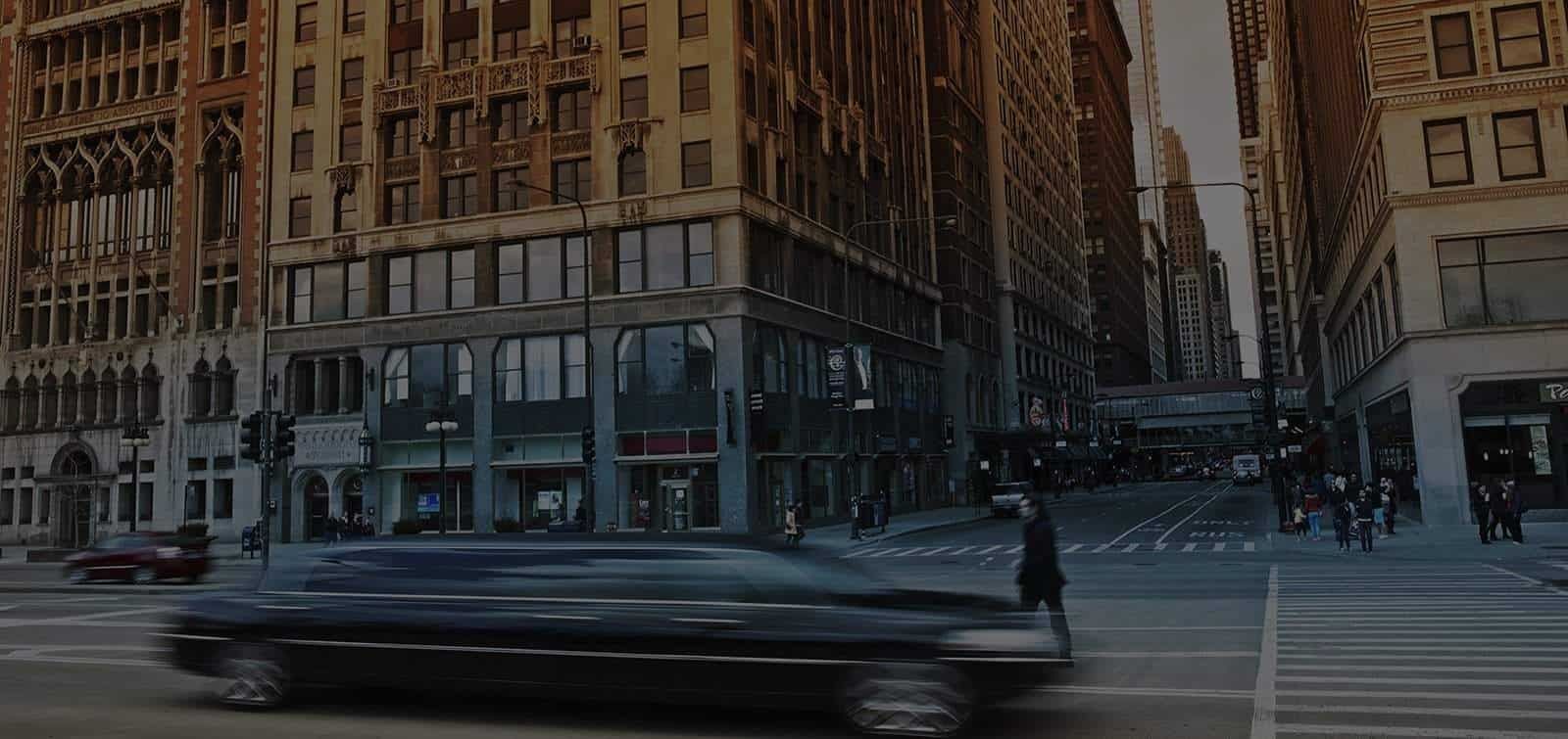A black car is driving down a city street.