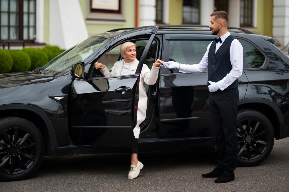 A man is helping a woman get out of a car.