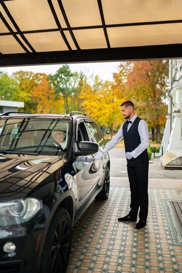 A man is standing next to a black car in a garage.