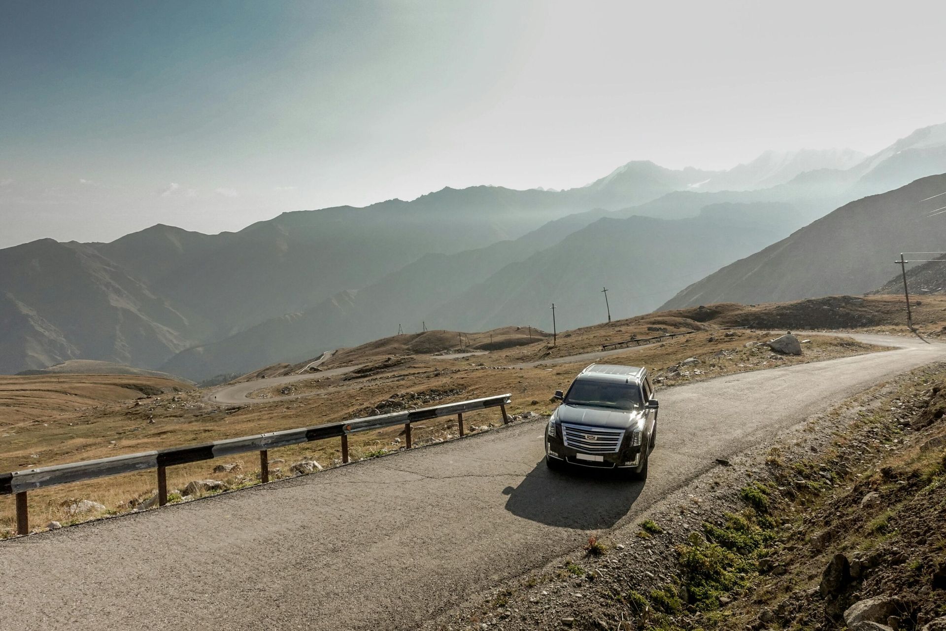 A white suv is driving down a mountain road.