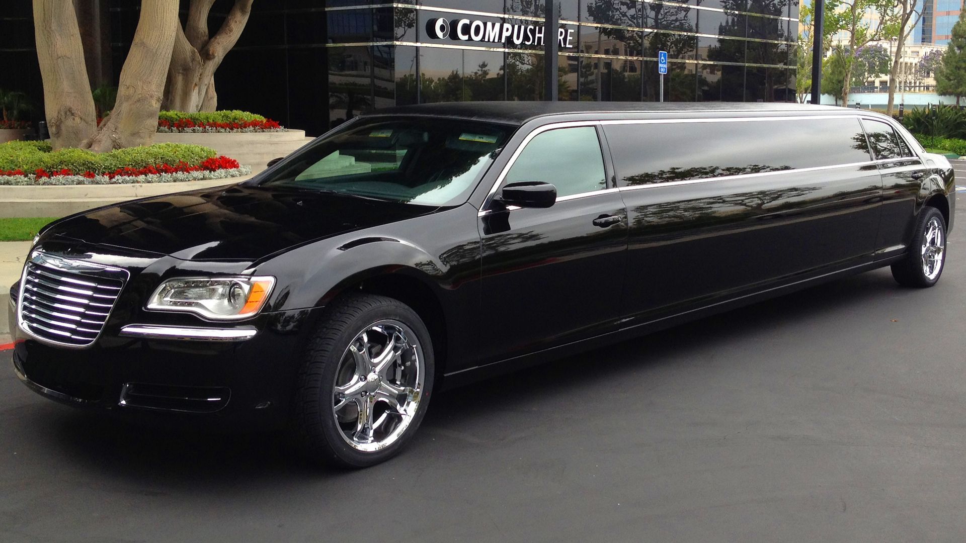A black limousine is parked in front of a building.
