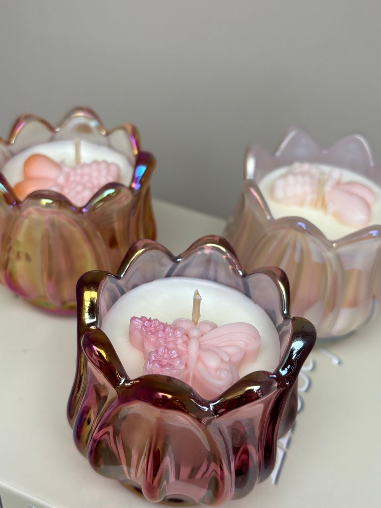 Drie tulpvormige kaarsen van iriserend roze glas staan ​​op een boek.