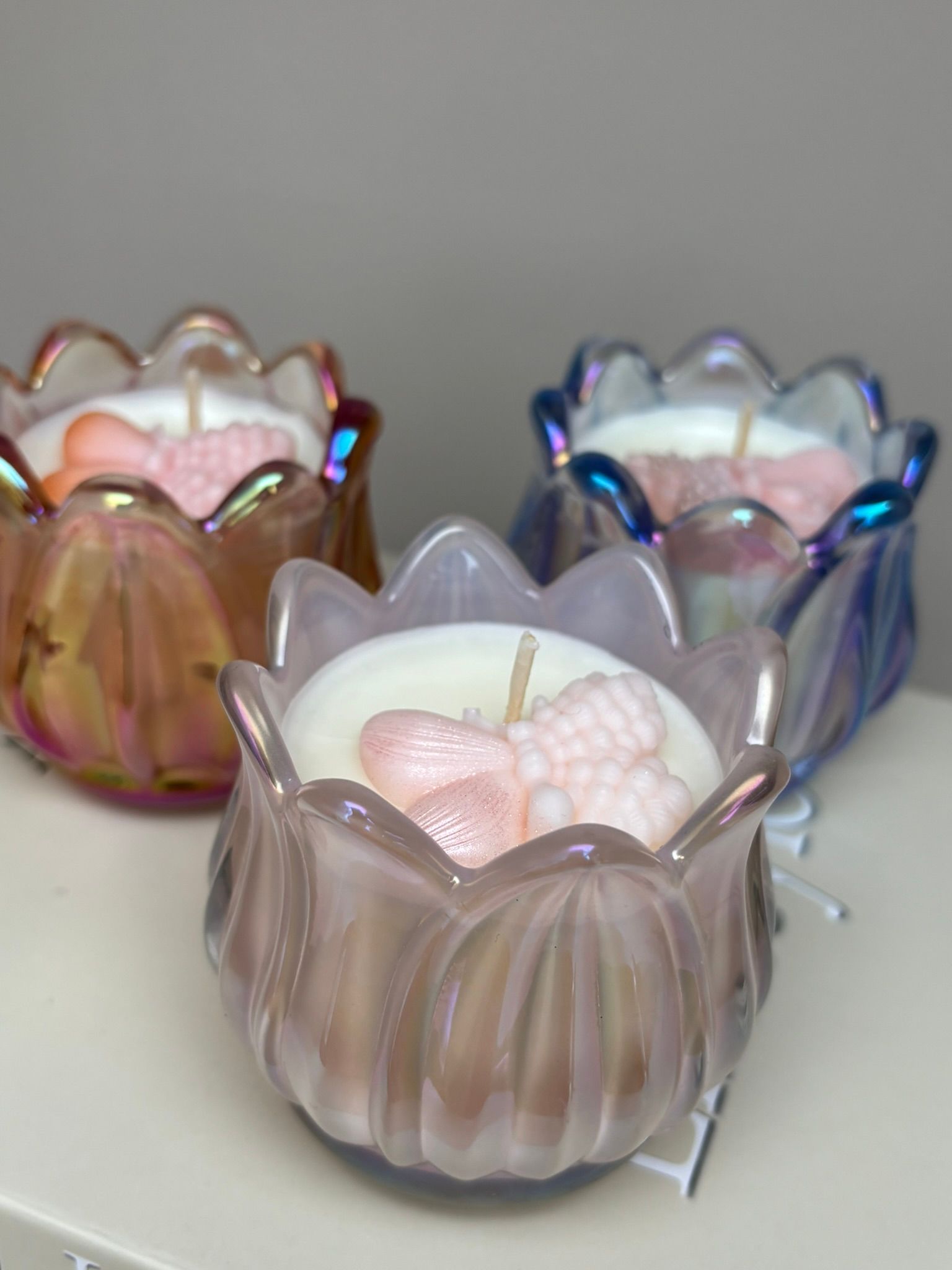 Drie tulpvormige, iriserende glazen kaarsen bovenop een boek met 'Artful Lifestyle' op de rug.