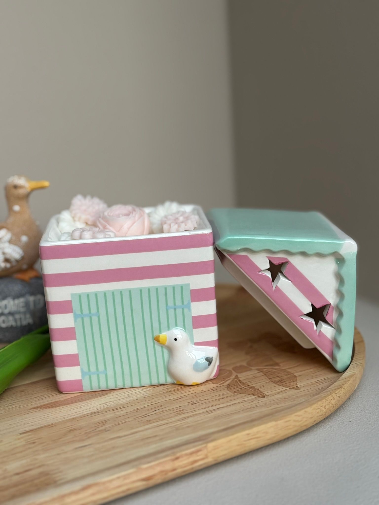 Een schaal gevuld met kleine, decoratieve wasbloemen in lichtroze en witte tinten.