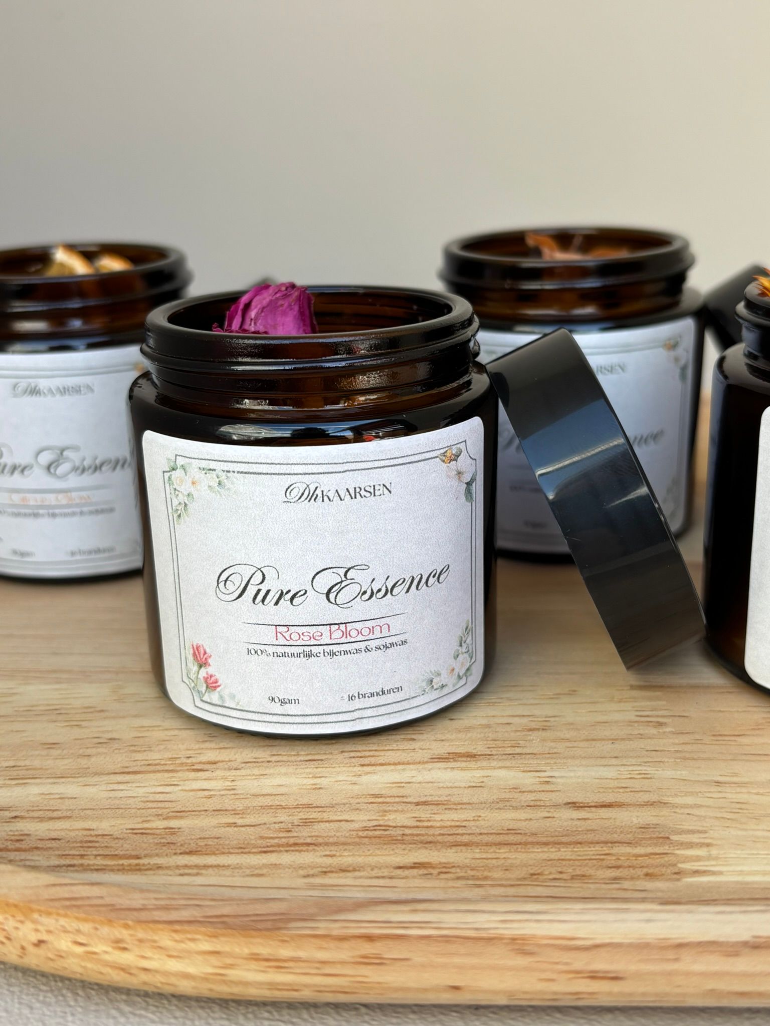 Kleine amberkleurige glazen potjes gevuld met kaarsen, afgewerkt met gedroogde bloemen, staan ​​op een houten plank.