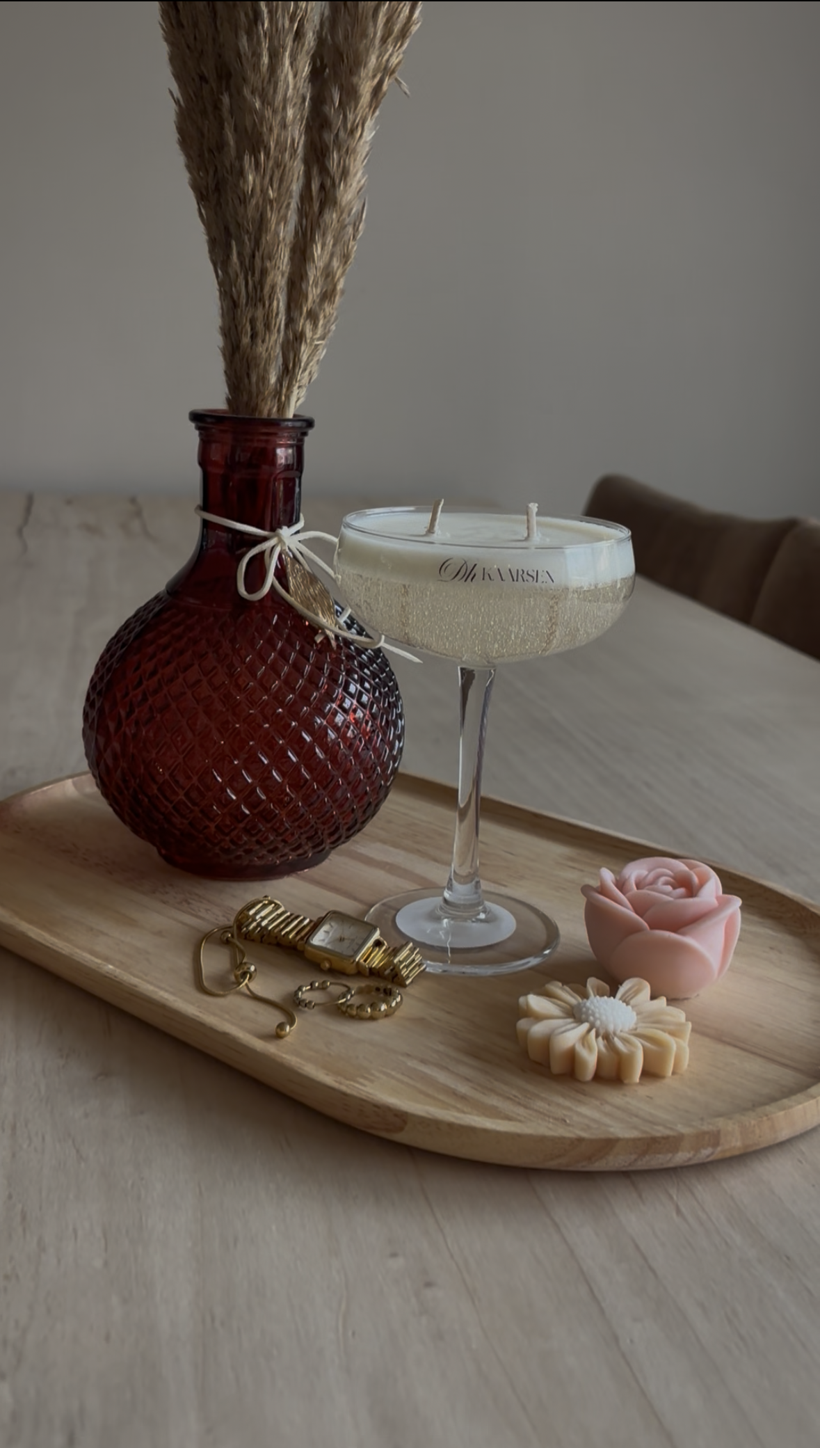 Een witte cocktail in een coupeglas, naast witte bloemen en een fles water op een tafel.