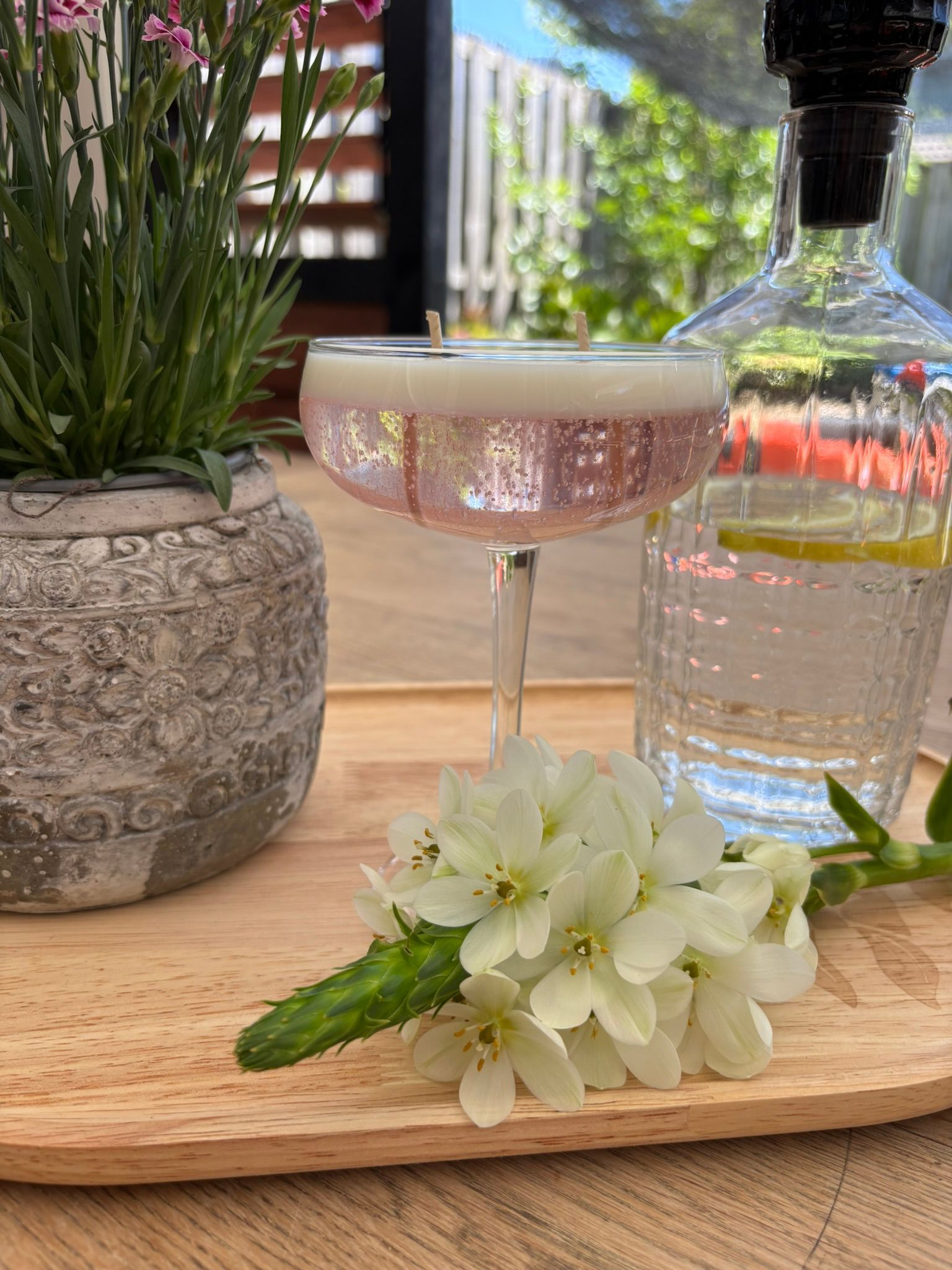 Cocktail met komkommer- en citroengarnituur naast heldere citroenen op een houten tafel.