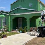 A green house with a horse statue in front of it.