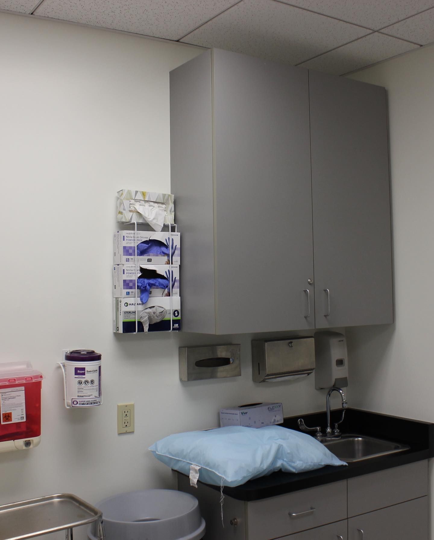 A room with a sink and gloves on the wall