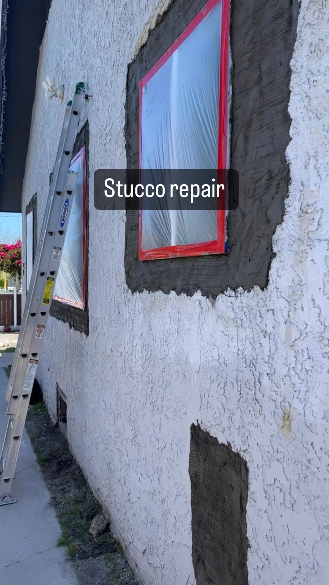 A ladder is sitting on the side of a building next to a window.