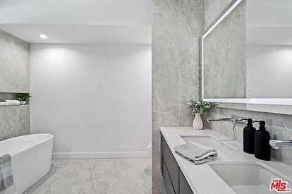 A bathroom with a tub , sink and mirror.