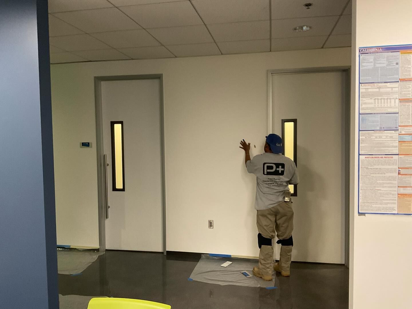 A man is painting a wall with the letter p on his back