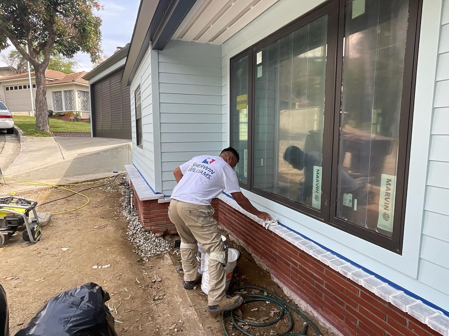 A man is painting the side of a house.