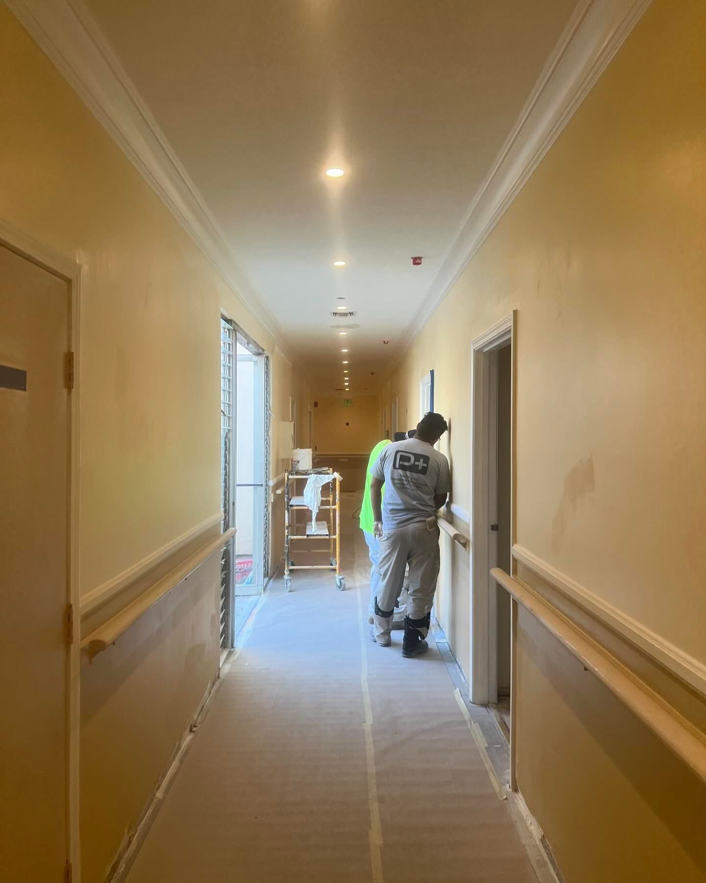 A group of people are standing in a long hallway.