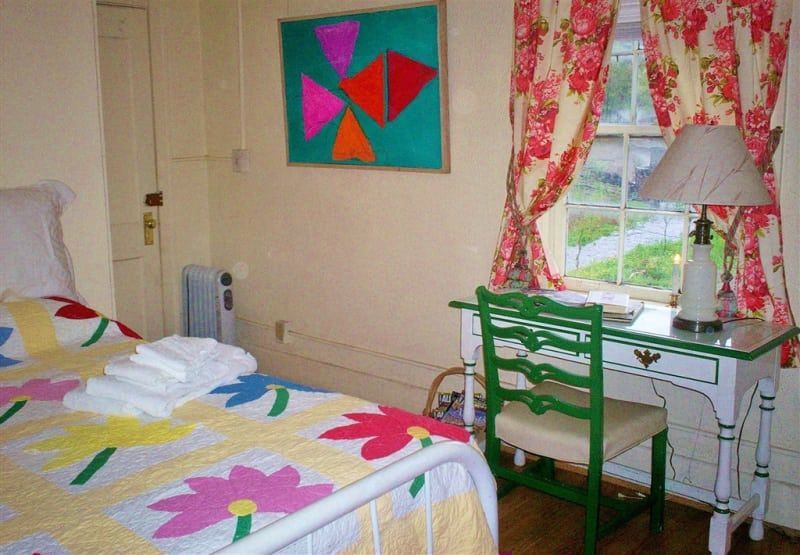 A bedroom with a bed a desk and a lamp