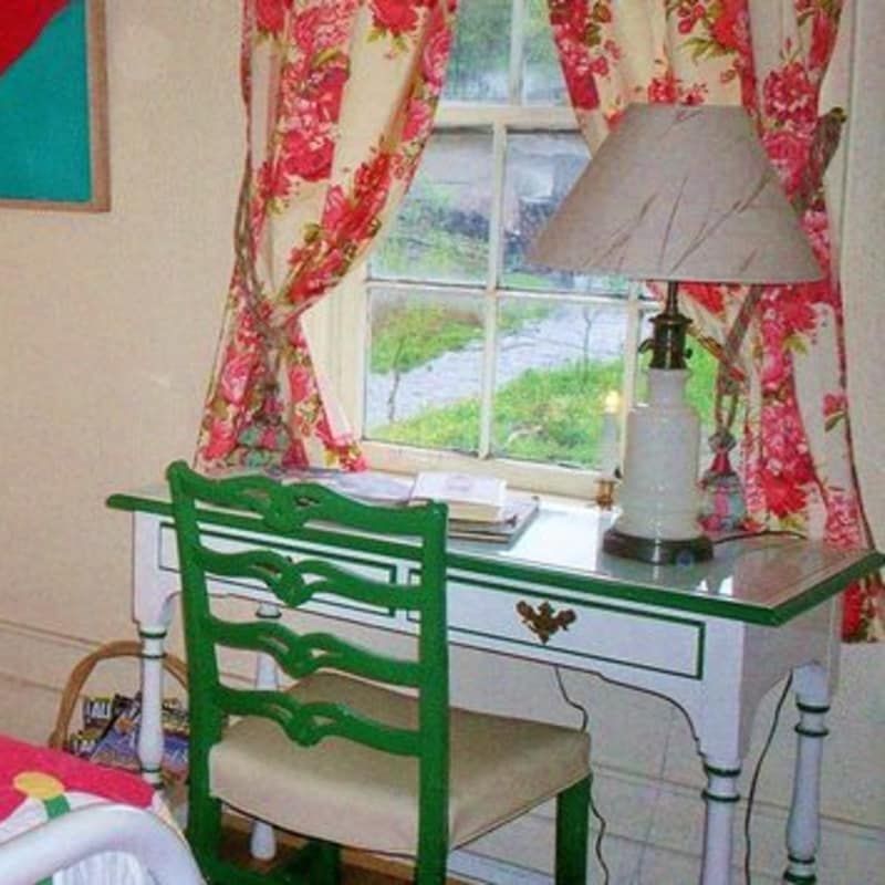 A green chair sits at a desk in front of a window