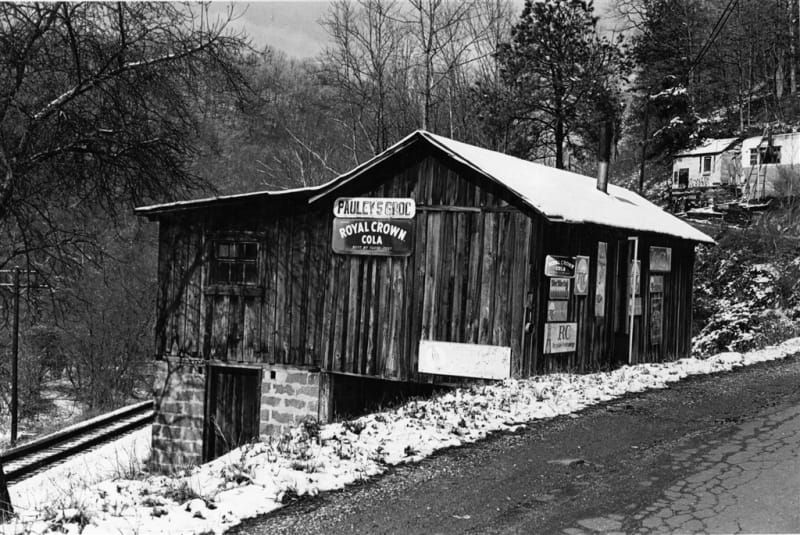 A black and white photo of a wooden building with a sign that says welcome