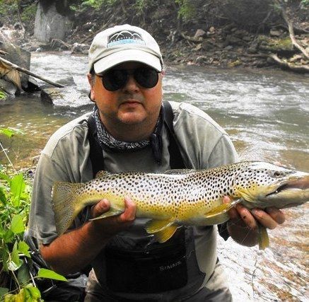 A man is holding a large brown trout in his hands