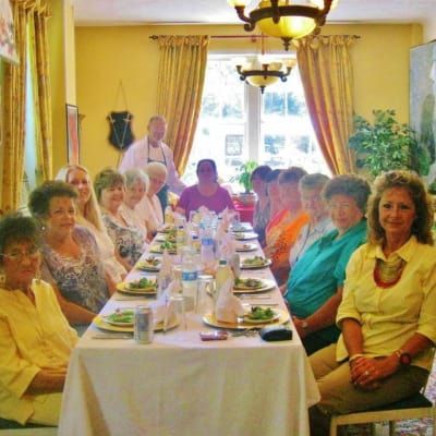 A group of people are sitting around a long table with plates of food on it