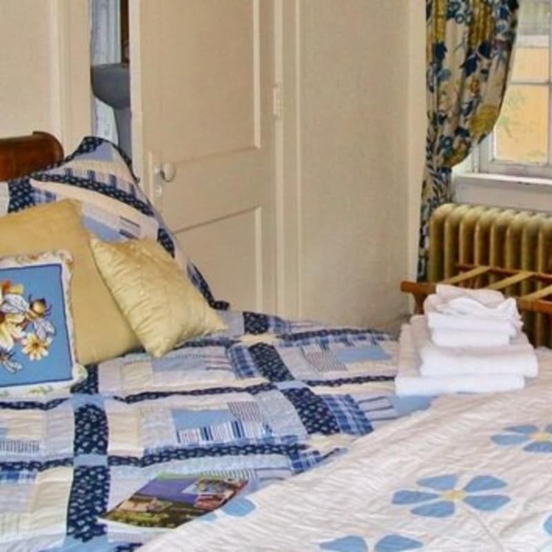 A bed with a blue and white quilt and pillows