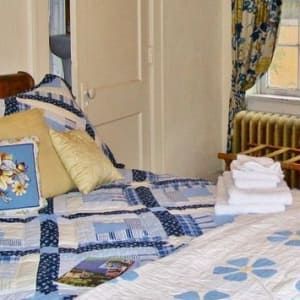 A bed with a blue and white quilt and pillows in a bedroom.