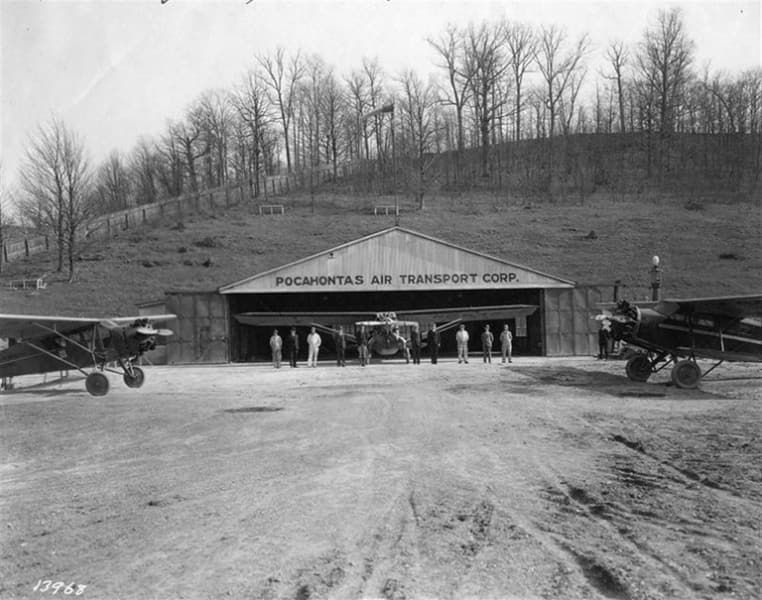 A black and white photo of planes in front of a building that says poconotas air transport corp