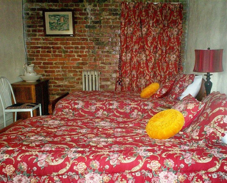 A bedroom with two beds and a brick wall