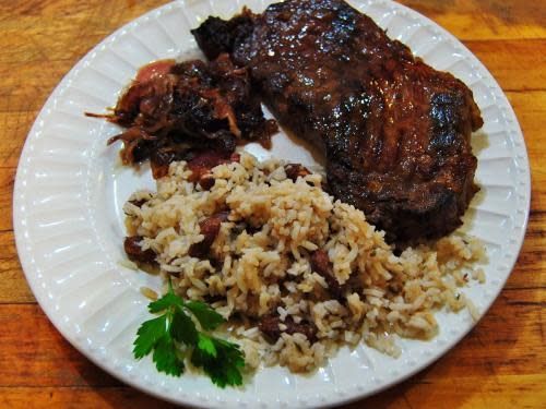 A white plate topped with rice and meat on a wooden table
